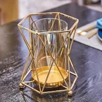 Vas kaca bening berbentuk silinder dengan dudukan bingkai logam geometris berwarna emas.